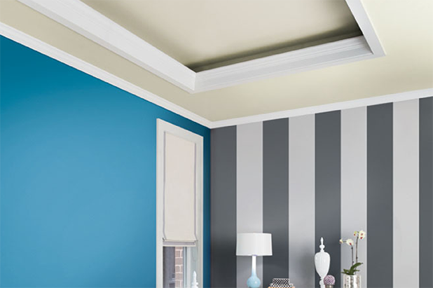 A dining room with furniture and accents has a striped accent wall painted the colors charcoal black and dusky grey. 