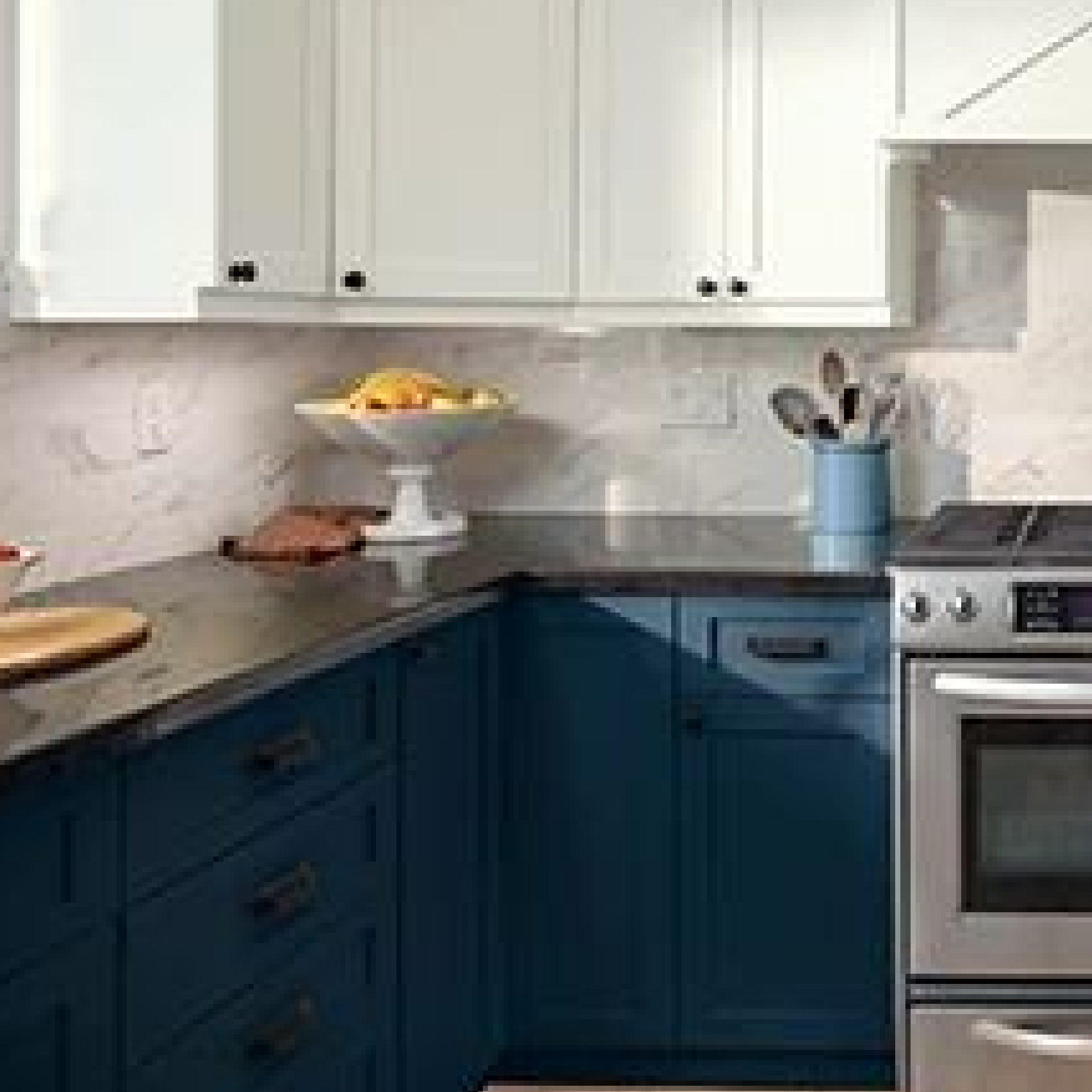 White cabinets, marble backsplash, stainless steel oven and fruit bowl. Cabinets are painted Deep Sky Blue.
