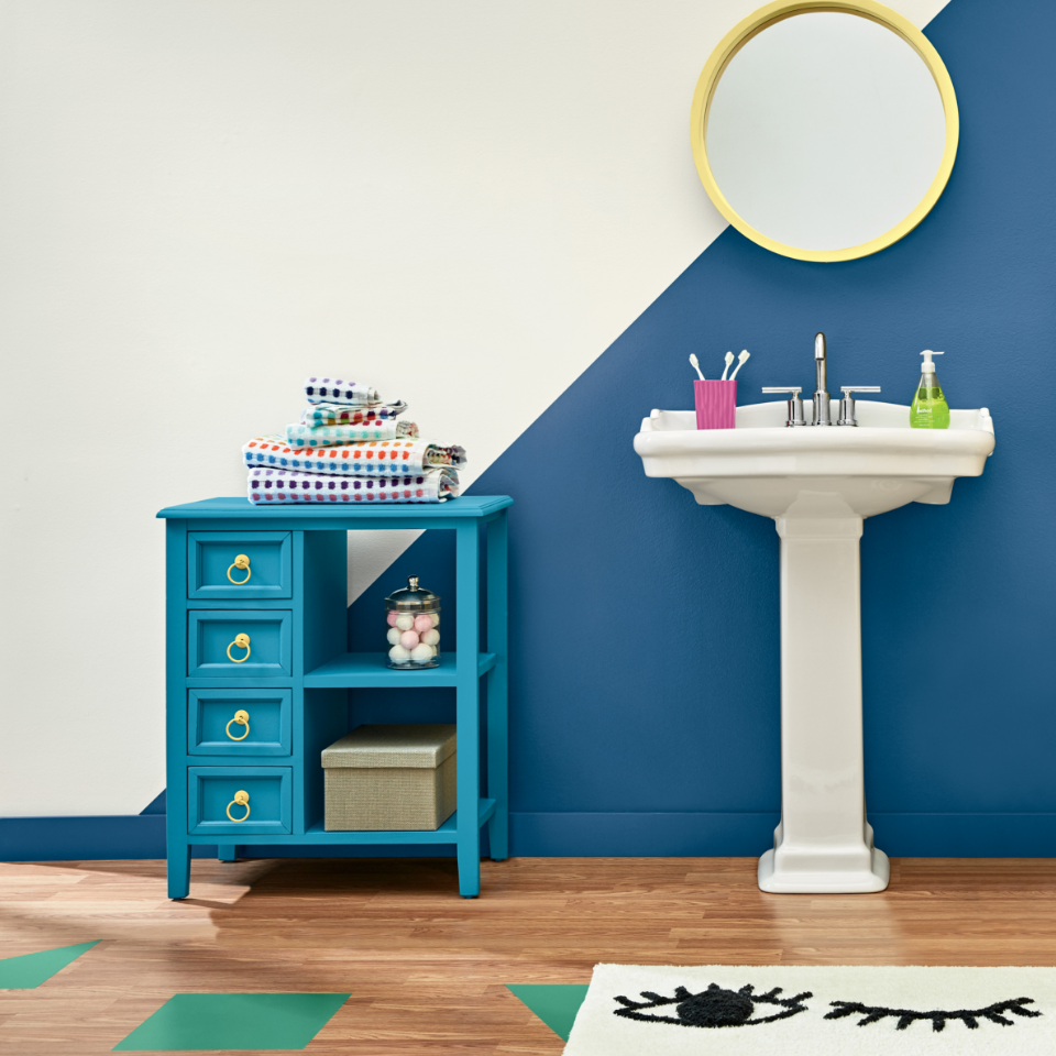 Bathroom vanity with a gold-framed mirror and shelving. Wall painted in the colors off white and ribbon blue.