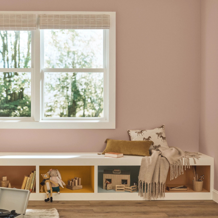 A playroom with a built-in bench that has cubbies for storage. Walls are painted neutral mauve mystery.