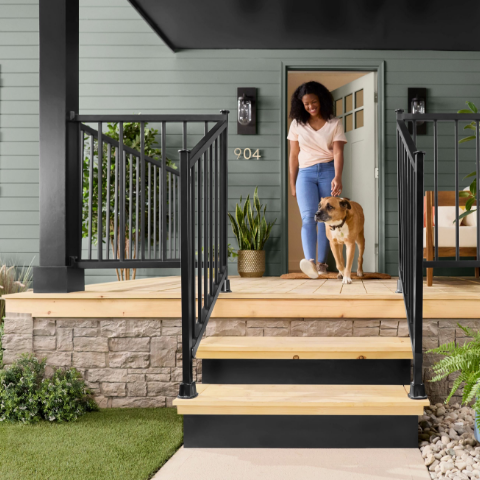 Woman walks her dog out on the front porch of her house. The exterior of the house is painted in the color Antiquated Pewter.