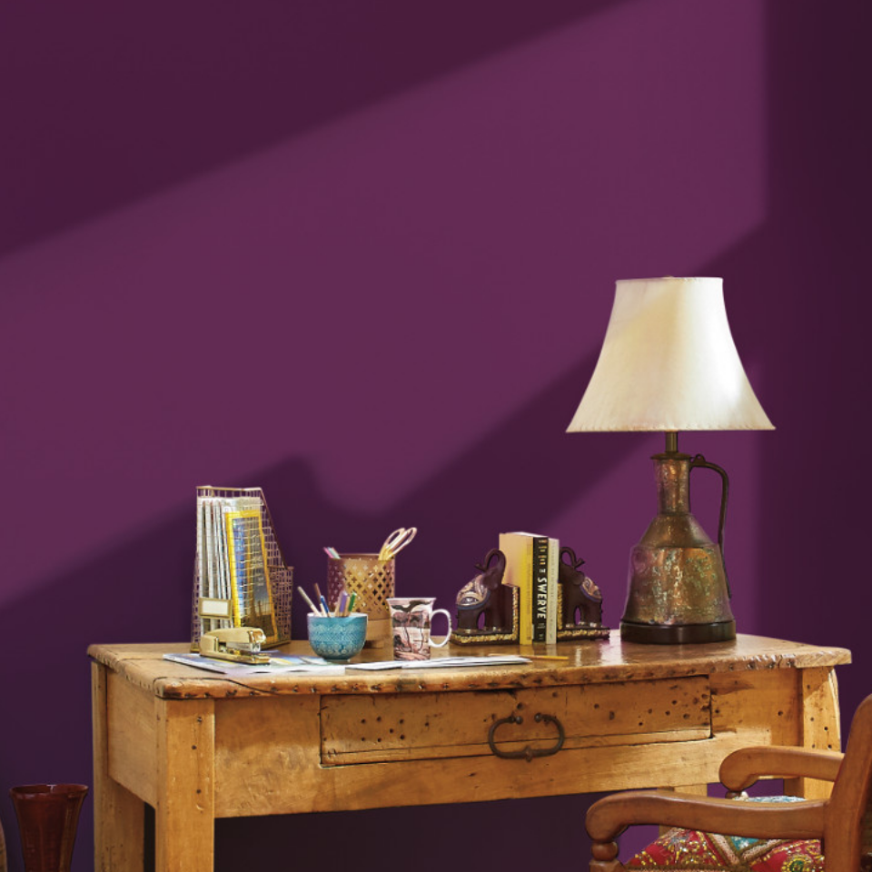 A wooden desk against a deep-purple wall.