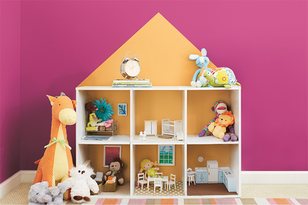 A dollhouse with stuffed animals and other toys sit in front of a magenta wall.