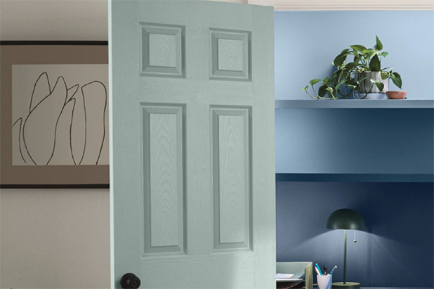 A home office situated inside of a closet with French doors painted light teal. Wall and shelves in office are darker blue. 