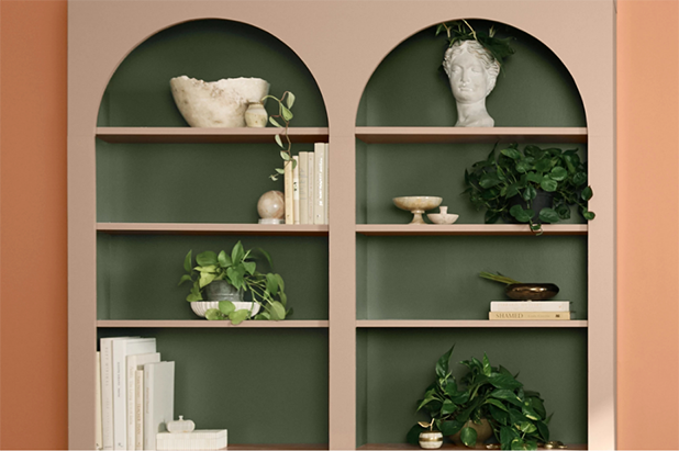 Curated shelving with arches at the top. Back wall of shelving is dark green, shelves and frame are mauve mystery. 