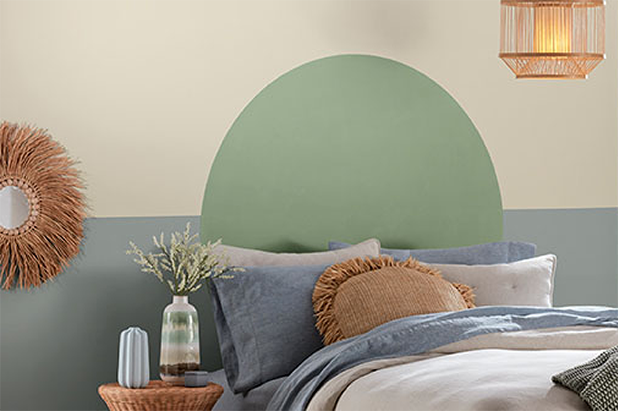 Bedroom wall with beige and grey horizontal pattern with a large green circle painted above the headrest of bed.