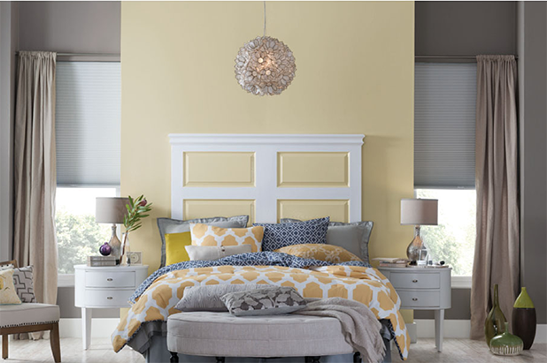 High ceilinged bedroom with tall windows. Wall above the head of bed is painted light yellow.