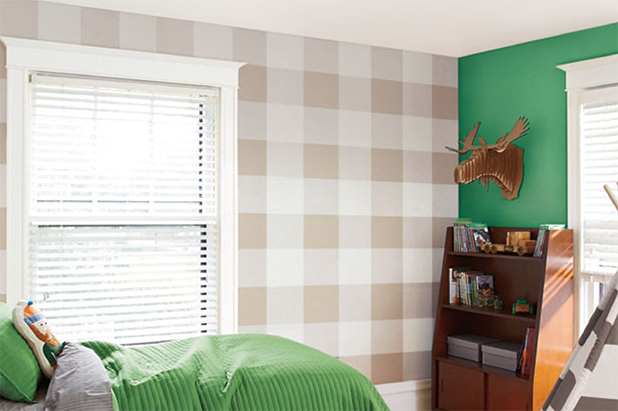 A child’s playroom with one wall painted and a matching bedspread. Another wall is painted in a buffalo check plaid pattern.