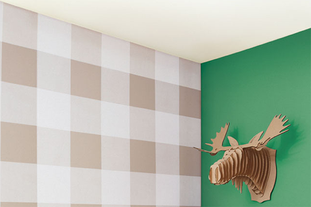 Corner walls of a child’s playroom. One wall is painted botanic green, another wall is painted a buffalo check plaid pattern.