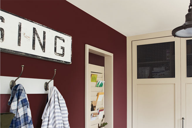 Mudroom with coats hanging on hooks and a window shutter organizer. The wall is painted in the color ground coffee. 