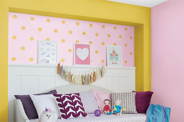 A whimsical nursery with a comfy trundle, a white cat and a playful yellow polka dot pattern on a pink wall.