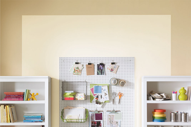 A smaller crafting room with shelving and pegboard. A dual-toned wall is light beige framed by darker beige.  