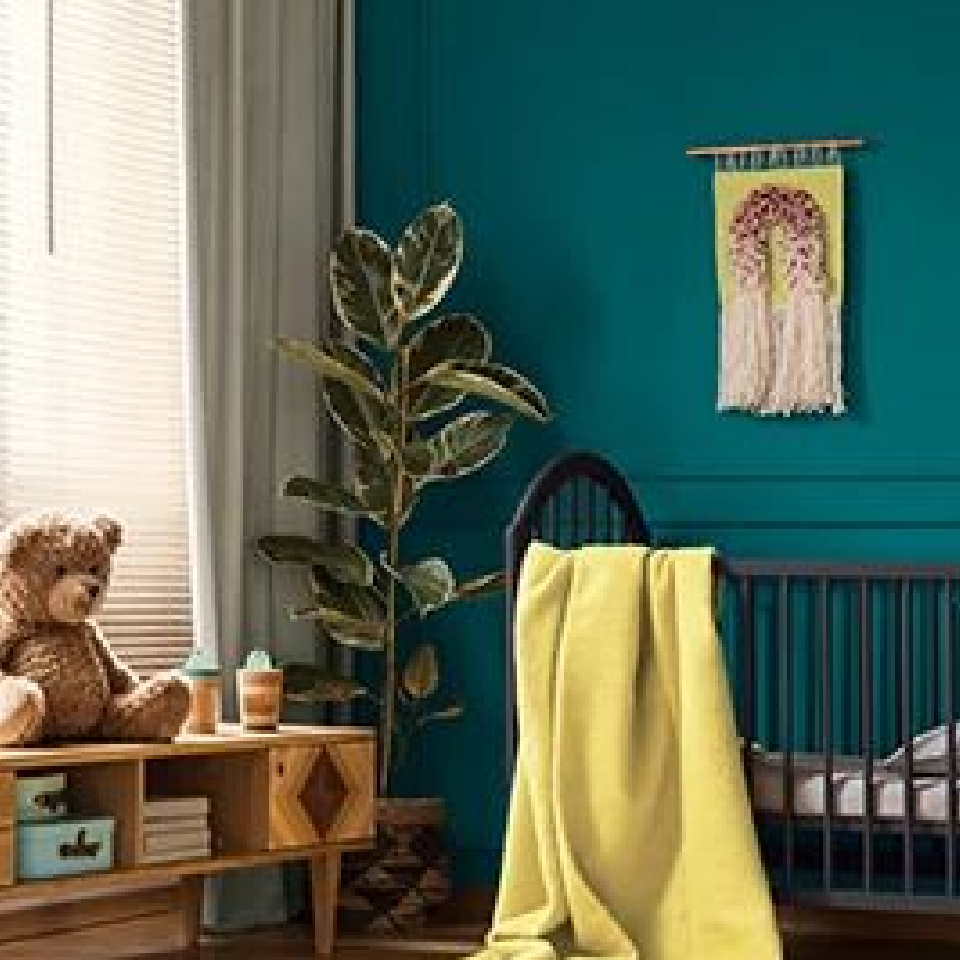 Nursery with a crib and yellow blanket, a console table with a teddy bear, and walls painted sea depths blue.