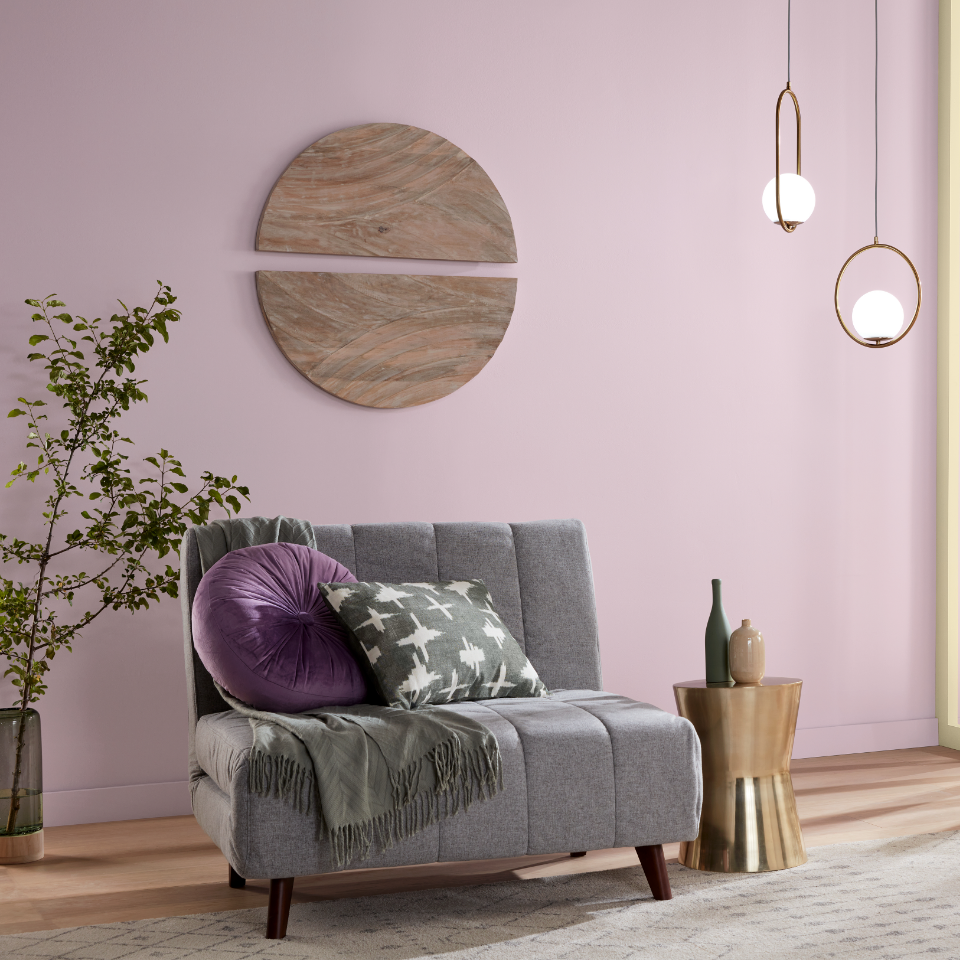 A modern living room with gray love seat, with a wood side table. Wall is painted purple.