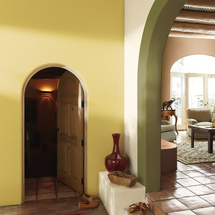 Large, Santa Fe style living space, with an arched doorway opening to a living room. Walls painted exotic yellow.