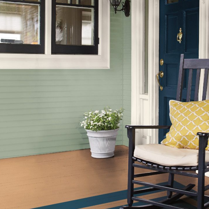 Front porch of a home with rocking chairs. A blue front door and cypress garden siding on the house.